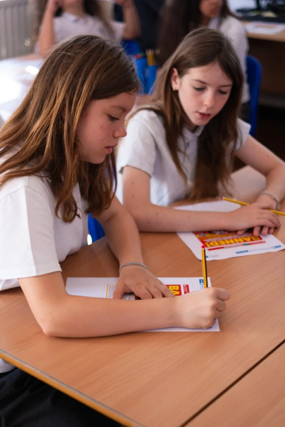 Two pupils working with pencils and classroom activity sheets