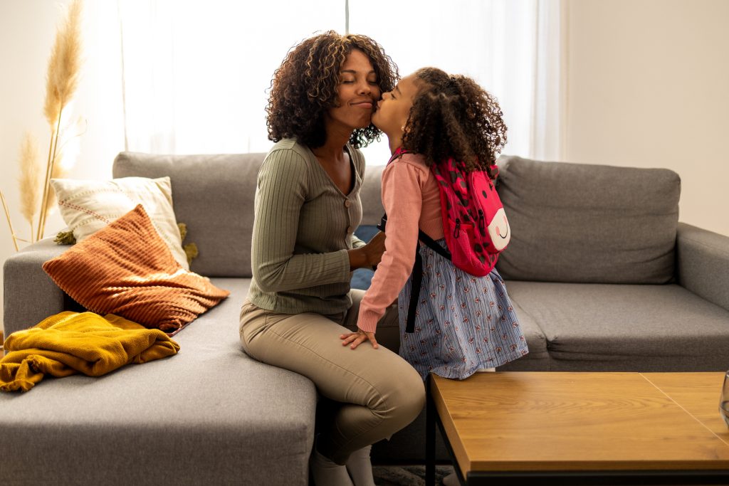 A young African American mother preparing her little daughter for school