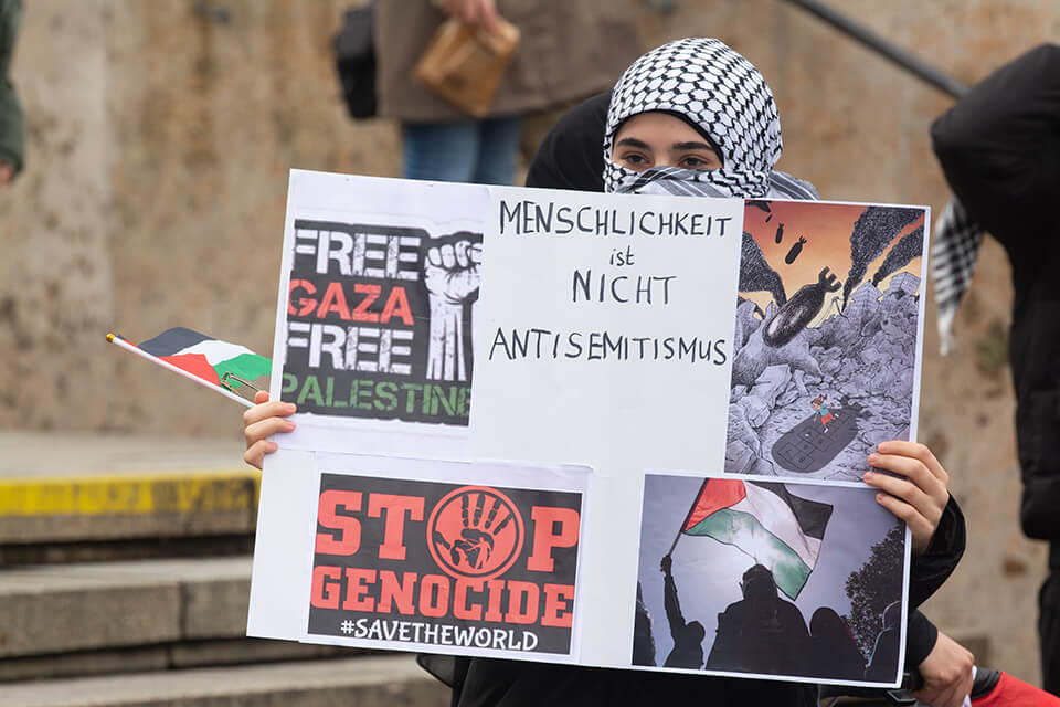 A pro-Palestine protester in Germany has a sign that reads “Humanity is not anti-Semitism”